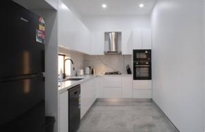 a kitchen with white cabinets and black appliances at Brand New Elegant House in Marsden Park
