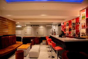 a bar in a restaurant with red chairs and a counter at Nirvana City Hotel in Benin City