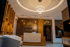 a man sitting at a counter in a lobby at Nirvana City Hotel in Benin City