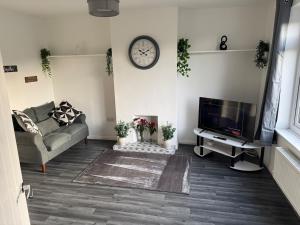 a living room with a couch and a clock on the wall at Rowe Terrace Workington in Workington