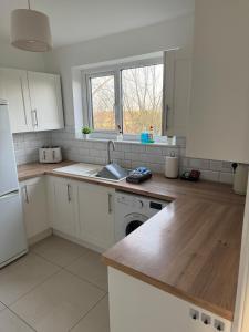 a kitchen with white cabinets and a sink at Rowe Terrace Workington in Workington