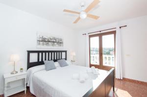 a white bedroom with a bed and a ceiling fan at Villa Can Canaleta by Sonne Villas in Cala Galdana +68 photos