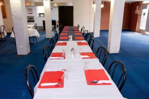 a row of long tables with red napkins on them at Commercial Hotel in Birchip