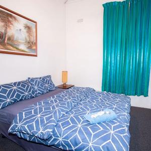 a bedroom with a bed with a blue and white comforter at Commercial Hotel in Birchip
