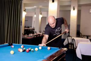 a man playing pool with a cue on a pool table at Commercial Hotel in Birchip