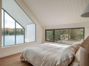 a bedroom with a bed and two large windows at Wild Pond Villa in Mansonville