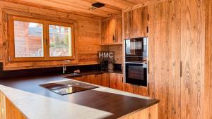 a kitchen with wooden walls and a counter top with a microwave at Agane skis aux pieds jacuzzi et vue montagne in Les Angles