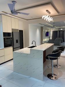 a kitchen with a white counter and stools at 1BR Ultra Modern Apartment in Gbawe in Gbawe