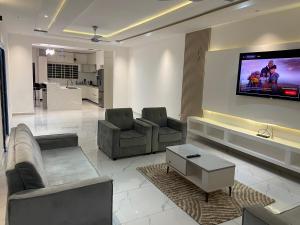a living room with couches and a flat screen tv at 1BR Ultra Modern Apartment in Gbawe in Gbawe