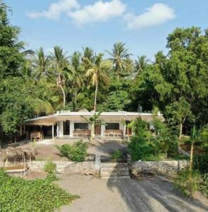 a large white house with palm trees in the background at East Lombok Dive Hotel - Rooms on the beach with seaview in Labuhanpandan