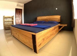 a large wooden bed with blue pillows in a room at East Lombok Dive Hotel - Rooms on the beach with seaview in Labuhanpandan