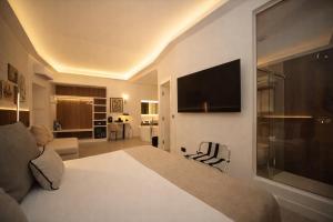 a hotel room with a bed and a flat screen tv at Mamalu - Corso Umberto 35 - Studios and Suites in Naples