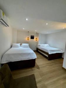 a bedroom with two beds with white sheets and wood floors at SUNSET BEACH in Playa Blanca