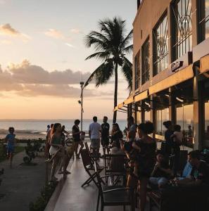 a group of people sitting outside of a building on the beach at Studio Aconchegante no Number One Flat com vista mar in São Luís