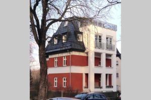 un edificio rojo y blanco con un árbol delante de él en Apartement in Stadtvilla, en Berlín