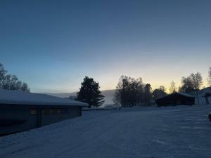 a snow covered road with a building and trees at Oppheim Resort - Pool, Sauna & Lake! in Vossevangen