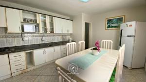 a kitchen with a table and a white refrigerator at Casa centro de Torres – 500 mts do mar in Torres