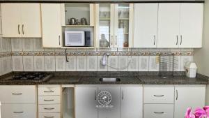 a kitchen with white cabinets and a microwave at Casa centro de Torres – 500 mts do mar in Torres +9 photos