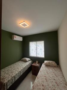 two beds in a room with green walls and a window at Impera House Terreo Ar nos 2 quartos in Imperatriz