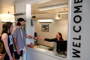 a man and a woman shaking hands in an office at The Brownston Hostel in Wanaka