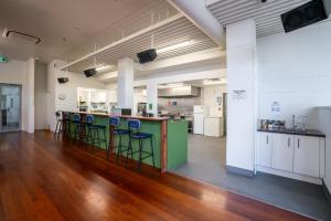 a large room with a green counter with stools at The Brownston Hostel in Wanaka