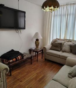 a living room with a couch and a tv on the wall at Mi Casa Elena in Morelia