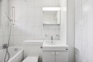 a white bathroom with a sink and a toilet at Very centrally located studio - Crown 15 in Zurich +4 photos