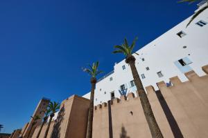 a building with palm trees in front of it at La Douiria Essaouira Medina in Essaouira