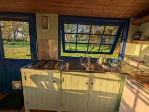 a kitchen with a sink and a stove and windows at Jay's Cabin in Skibbereen