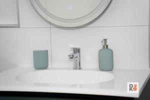 a bathroom sink with two soap dispensers and a mirror at Studio-Apartament 101 free Parking Domus Kushal in Viersen +36 photos