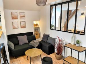 a living room with a black couch and a table at Le Repères des sommeliers - Bail Partner in Auxerre +27 photos