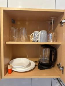 a cupboard with plates and glasses and a coffee maker at Studio Apartment - Neufelden in Neufelden