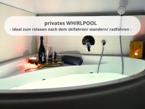 a bath tub with a bottle of wine in it at FeWo Schwarzwaldschick Feldberg I Bergurlaub I Balkon I Whirlwanne I Tiefgarage I HochschwarzwaldCard inkl in Feldberg