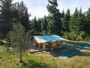 a small house with a blue roof in a field at Cabure in Epuyén