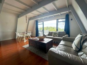 a living room with a couch and a table at Aroha A-Frames - Bush & Beach Retro Retreat in Coromandel Town