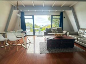 a living room with a couch and a table at Aroha A-Frames - Bush & Beach Retro Retreat in Coromandel Town