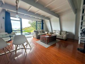 a living room with a couch and a table at Aroha A-Frames - Bush & Beach Retro Retreat in Coromandel Town