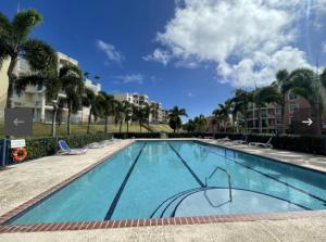 a large swimming pool with chairs and palm trees at Luxury Apartment- 3 Bedrooms in Ceiba