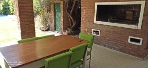 a wooden table with green chairs next to a brick wall at El buho in Roldán