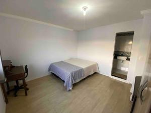 a small bedroom with a bed and a desk at Duplex 3 quartos 5 min da UFV in Viçosa