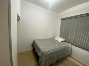 a small bedroom with a bed in a white room at Duplex 3 quartos 5 min da UFV in Viçosa