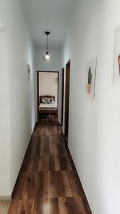 ein Flur mit weißen Wänden und Holzböden und ein Bett in der Unterkunft Refúgio Ibiúna in Ibiúna