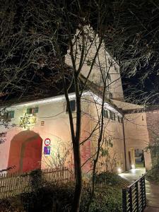 a white building with a red door next to a tree at Historischer Stadtturm Fürstentor Greding in Greding +4 photos