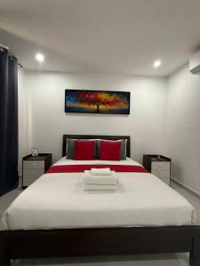 a bedroom with a large white bed with red pillows at Viva La Rosa Hometel in Anda