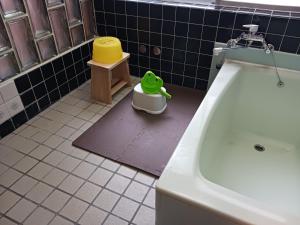 Ein Badezimmer, in dem ein grünes Spielzeug neben einem Waschbecken auf dem Boden liegt. in der Unterkunft もりたさんち in Taitsuri-shima