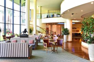 eine Lobby mit Stühlen, Tischen und Fenstern in der Unterkunft Pestana Grand Ocean Resort Hotel in Funchal