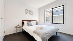 a white bedroom with a bed and a window at Lyra 2026 Home by GoodLive in Beveridge