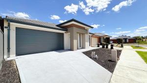 a house with a garage door in a driveway at Lyra 2026 Home by GoodLive in Beveridge