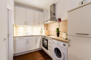 a kitchen with white cabinets and a washer and dryer at Ferienwohnung-Mour in Dahme