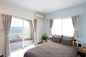 a bedroom with a bed and a balcony with the ocean at Ocean Terrace金武 in Kin